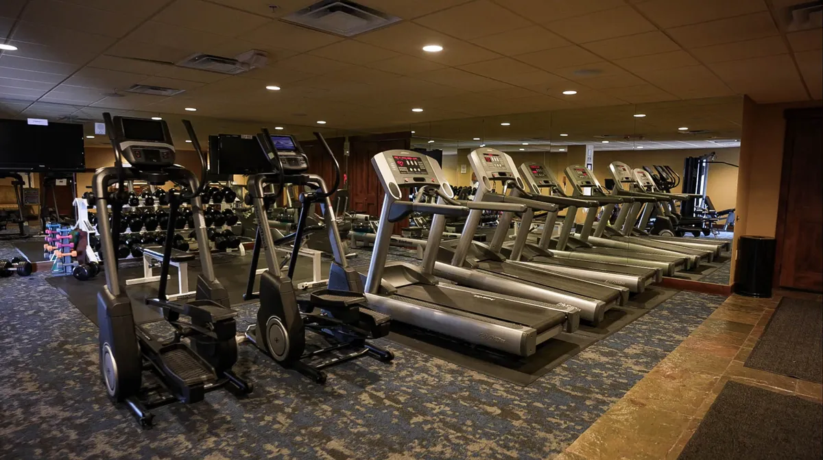 A well-equipped fitness center interior, featuring treadmills, ellipticals, and free weights. The space is bright and energetic, ideal for guests wanting to maintain their workout routines during their stay.