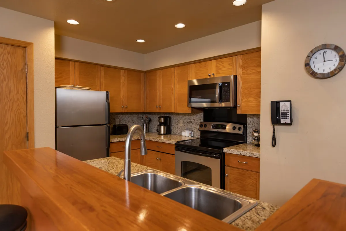 Here, stainless steel appliances and granite countertops frame a practical cooking space with wooden cabinetry and a well-organized sink area. The kitchen looks ready for anything from family recipes to late-night snacks, with an emphasis on functionality and comfort.